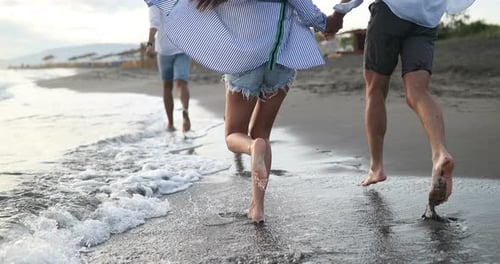 Group of Happy Friends Running on the Beach at Summer at Sunset