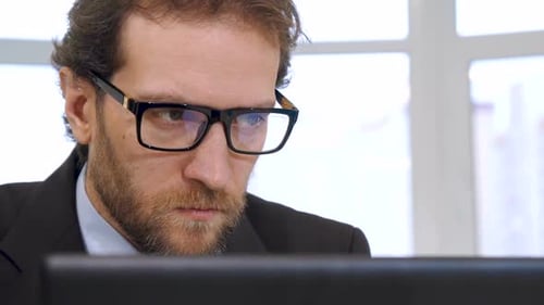 Man Wearing Glasses Looks at Computer