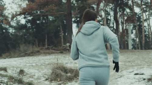 Fit woman jogging up the hill in winter