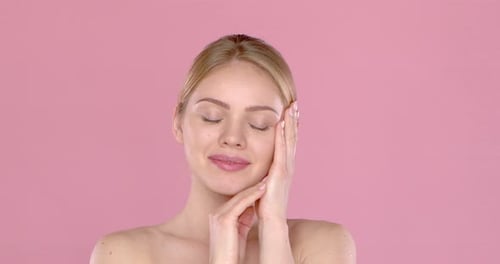 Blonde Woman Smiling, Hands on Face, Pink Background