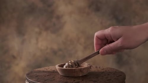 Honey drips from Wooden Dipper into Wooden Bowl
