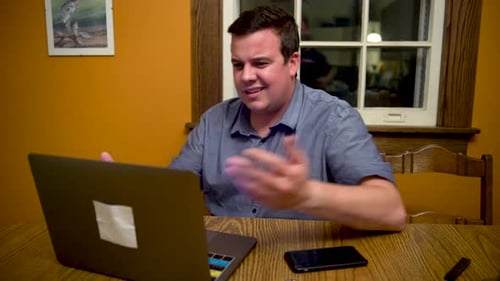 Man Typing on Laptop at Table in Home