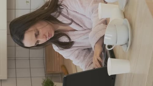 Tired Woman Working on Laptop in Kitchen