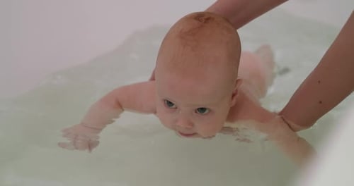 Infant Swimming in Bathtub with Adult Assistance
