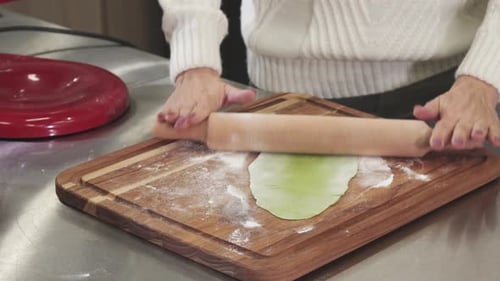 Cropped Shot of a Woman Rolling Out Green Dough with Herbs for Pasta