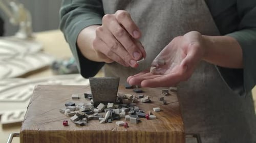 Manos masculinas recogen trozos de piedra rotos para trazar un patrón de mosaico