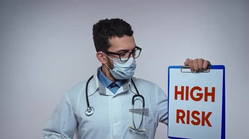 Médecin portant un stéthoscope avec avis de risque élevé écrit sur un panneau de soins de santé