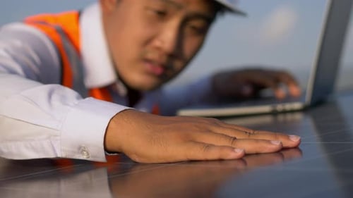 Young technician man working on laptop in solar farm