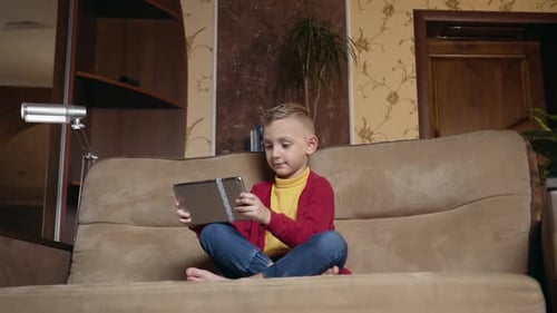 Child Using Tablet on Couch in Home