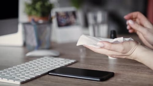 Handheld video of woman cleaning phone in the office. Shot with RED helium camera in 8K.
