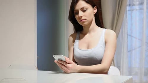 Young Woman Using Smartphone at Table Indoors