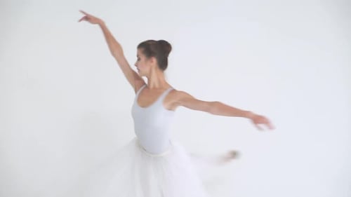 Elegante Frau in einem weißen Tutu tanzt Ballett und führt choreografische Elemente auf weißem Hintergrund auf