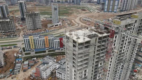 Survol du site de construction. Bâtiments de grande hauteur en construction et grues de construction