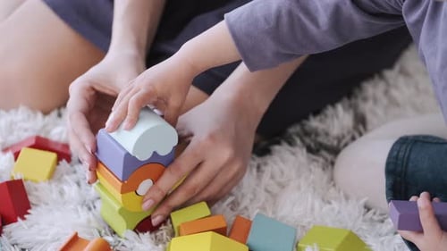 Young Adult and Child Playing with Wooden Blocks