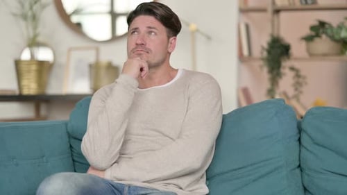 Mann mittleren Alters sitzt und denkt zu Hause