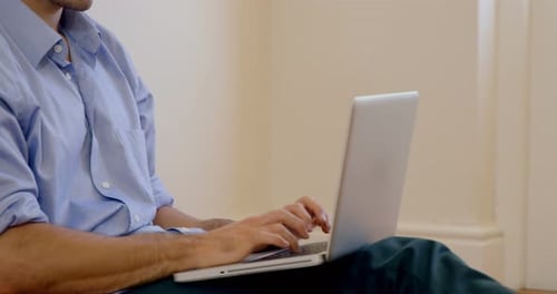 Man working on laptop while sitting on floor