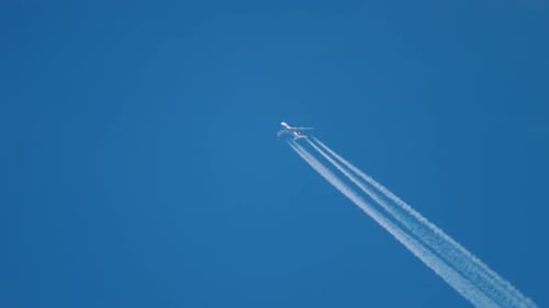 Commercial Airplane Soaring Through Blue Sky with Contrail