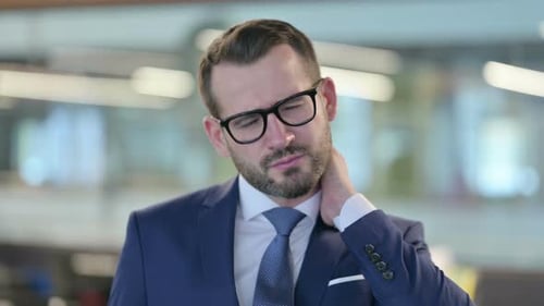 Man in Suit Rubs Stiff Neck in Office