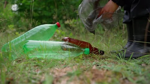 Una persona irreconocible recoge basura en el bosque en un paquete. Persona voluntaria en uniforme