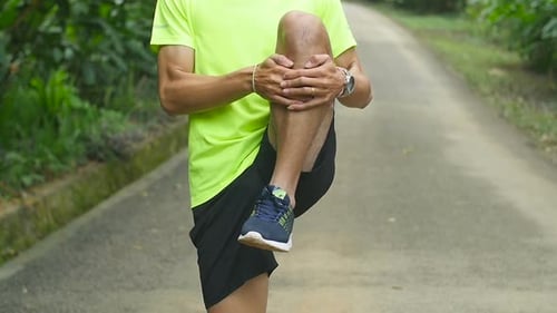 Man Stretching Leg in a Tropical Setting