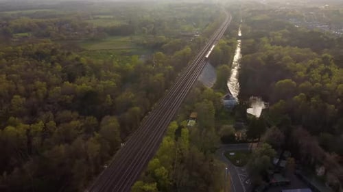 Bela vista aérea do trem viajando ao pôr do sol com floresta e campos