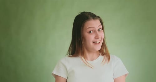 Happy Doubting Woman in Smiles Posing for Camera on Green