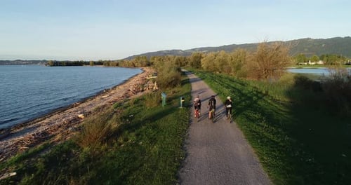 Aerial view of three person cycling a bike along Constance lake, Switzerland.