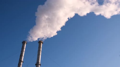 Smokestacks Emitting Smoke Against Blue Sky