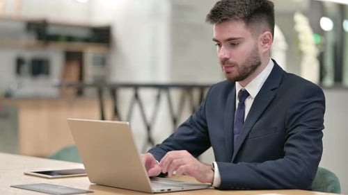 Focused Young Businessman Working on Laptop in Office