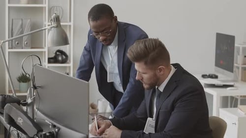 Two Multiethnic Fund Managers Analyzing Stock Market in Office