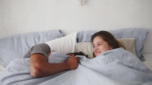 Vue rapprochée d'un couple multiracial heureux allongé dans son lit et riant