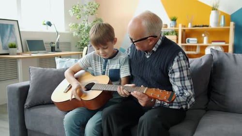 Slow Motion of Cheerful People Grandson and Grandfather Playing the Guitar at Home
