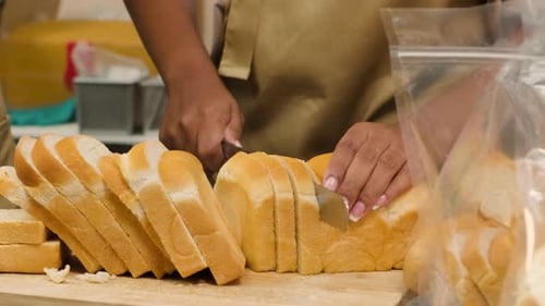 Woman slicing loaf of bread on wooden board