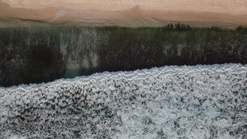 Aerial Top View of Ocean Waves Break on a Beach
