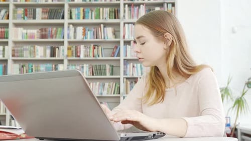 Charmante adolescente travaillant sur son ordinateur à la bibliothèque