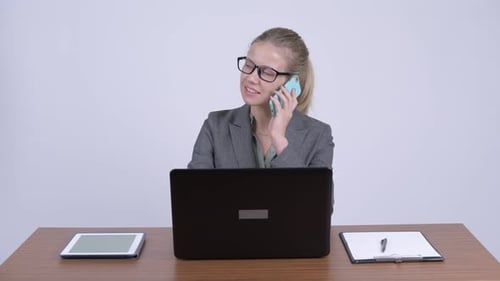 Business Woman Talking on Phone While Working on Laptop