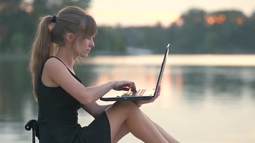 Young Woman Working Behind Laptop Sitting in Summer Park Outdoors