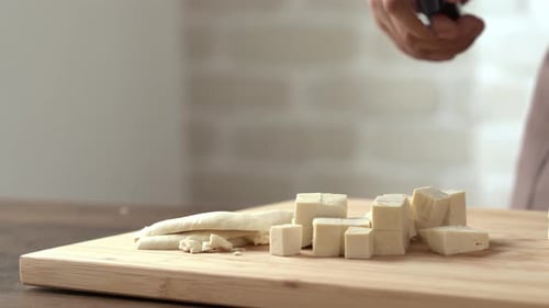 Adult Prepares Tofu Cubes on Cutting Board