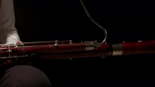 Woman sitting on chair in studio with bassoon on her lap picks it up and starts playing music