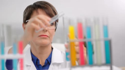 Female Scientist Examining Colorful Test Tubes in Lab