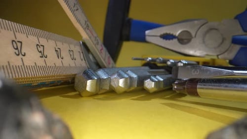 Close up dolly shot showing tools for work, measuring stock,screwdriver and hammer on yellow surface