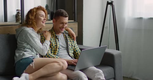 Smiling Couple Using Laptop Together on Couch