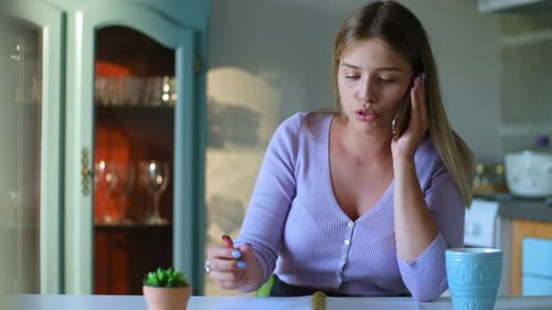 Woman on Phone Writing Notes at Home