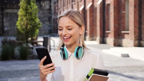 Smiling Woman Using Smartphone Outdoors in Urban Environment