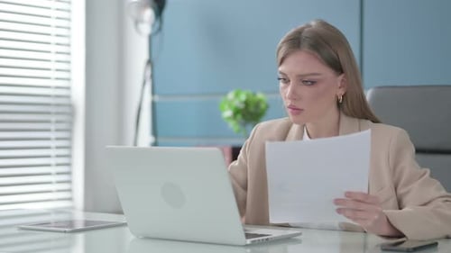 Young Woman Celebrates Success with Laptop in Office
