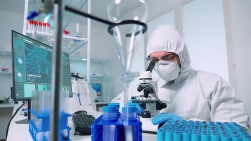 Scientist in Protective Suit Working with Microscope
