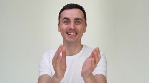 Fröhlicher glücklicher junger Mann klatscht in die Hände auf weißem Hintergrund.