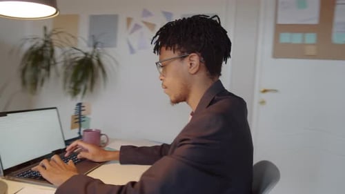 African American Man Typing on Laptop in Office during Workday