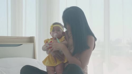 Mother Holding Baby with Toy Indoors