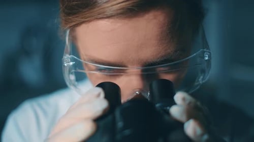 Woman Scientist Working With Microscope in Dark Lab